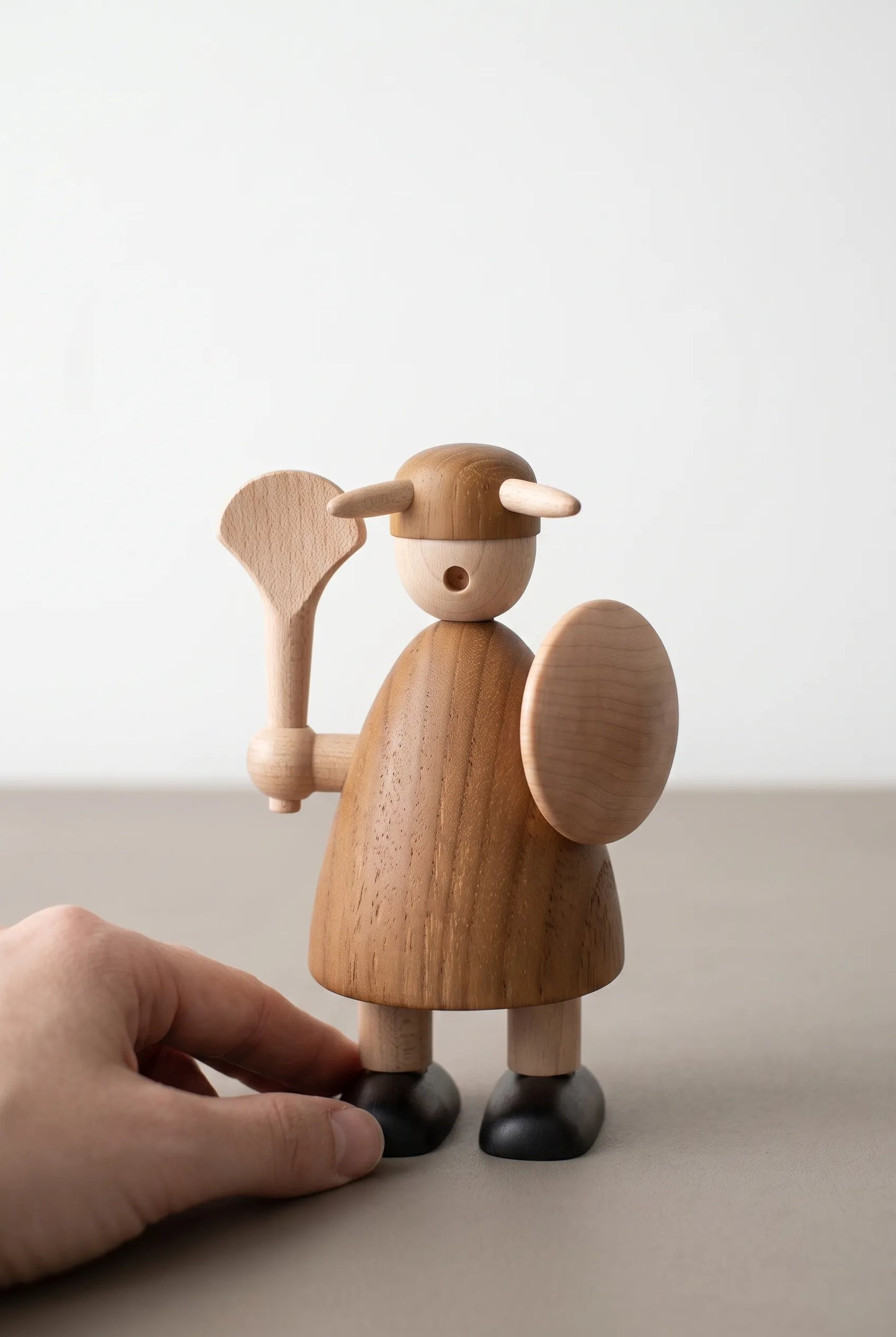 Nordic Mythos Viking Wood Sculpture crafted from Solid Teak and Natural Maple Wood with glare-free matte finish, touched gently by a relaxed hand at the lower frame edge.