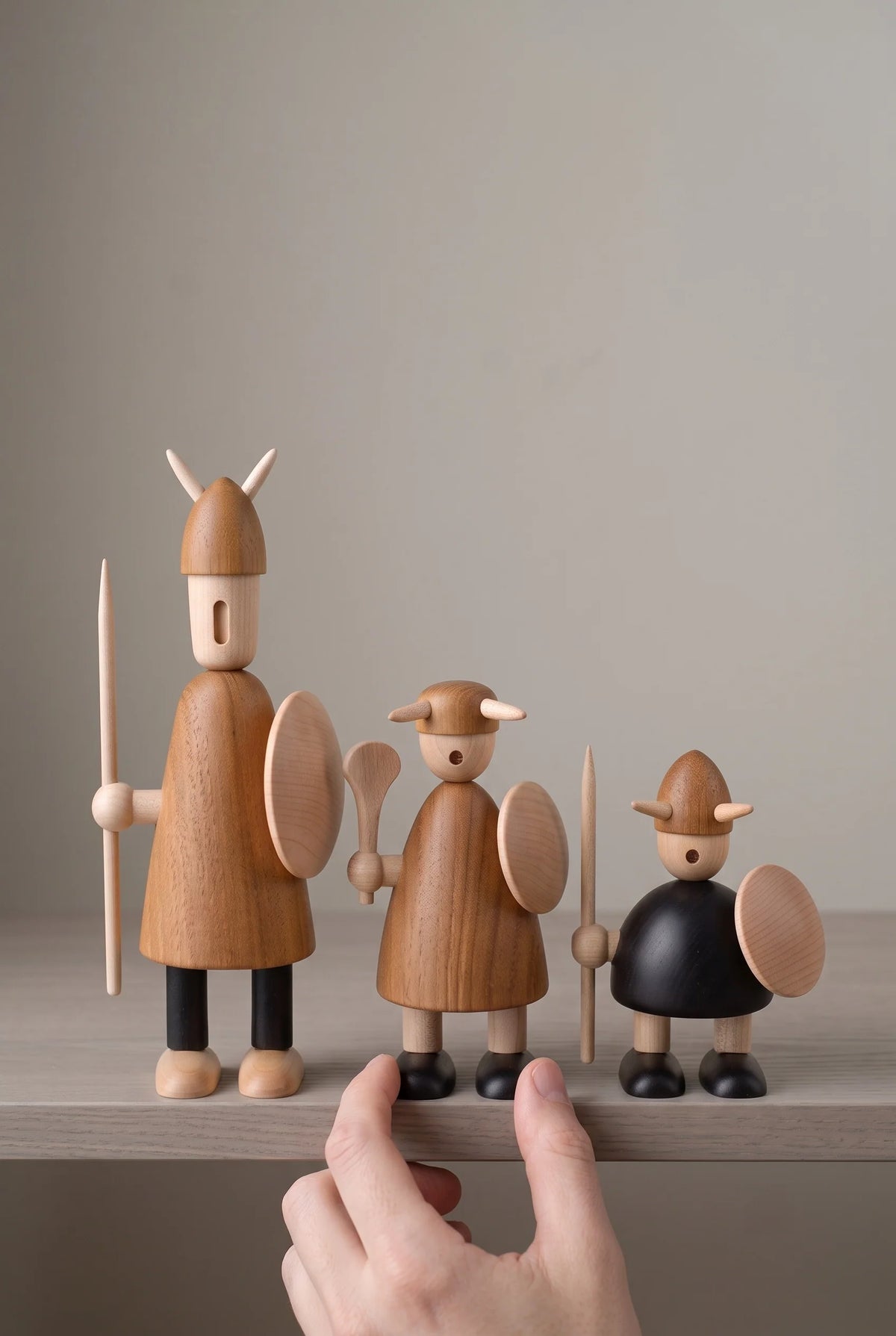 Nordic Mythos Viking Wood Sculptures crafted from Solid Teak and Natural Maple with Glare-free matte natural oil finish, touched gently by a relaxed hand at the lower frame edge.