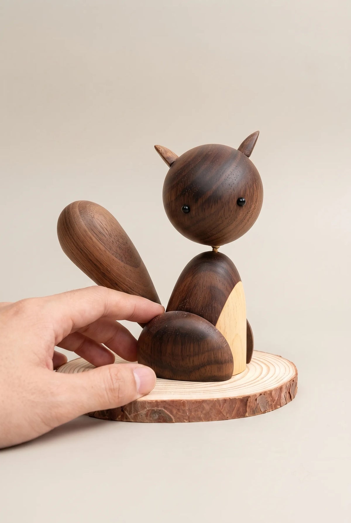 11 cm Nordic black walnut squirrel sculpture beside a relaxed hand for scale.