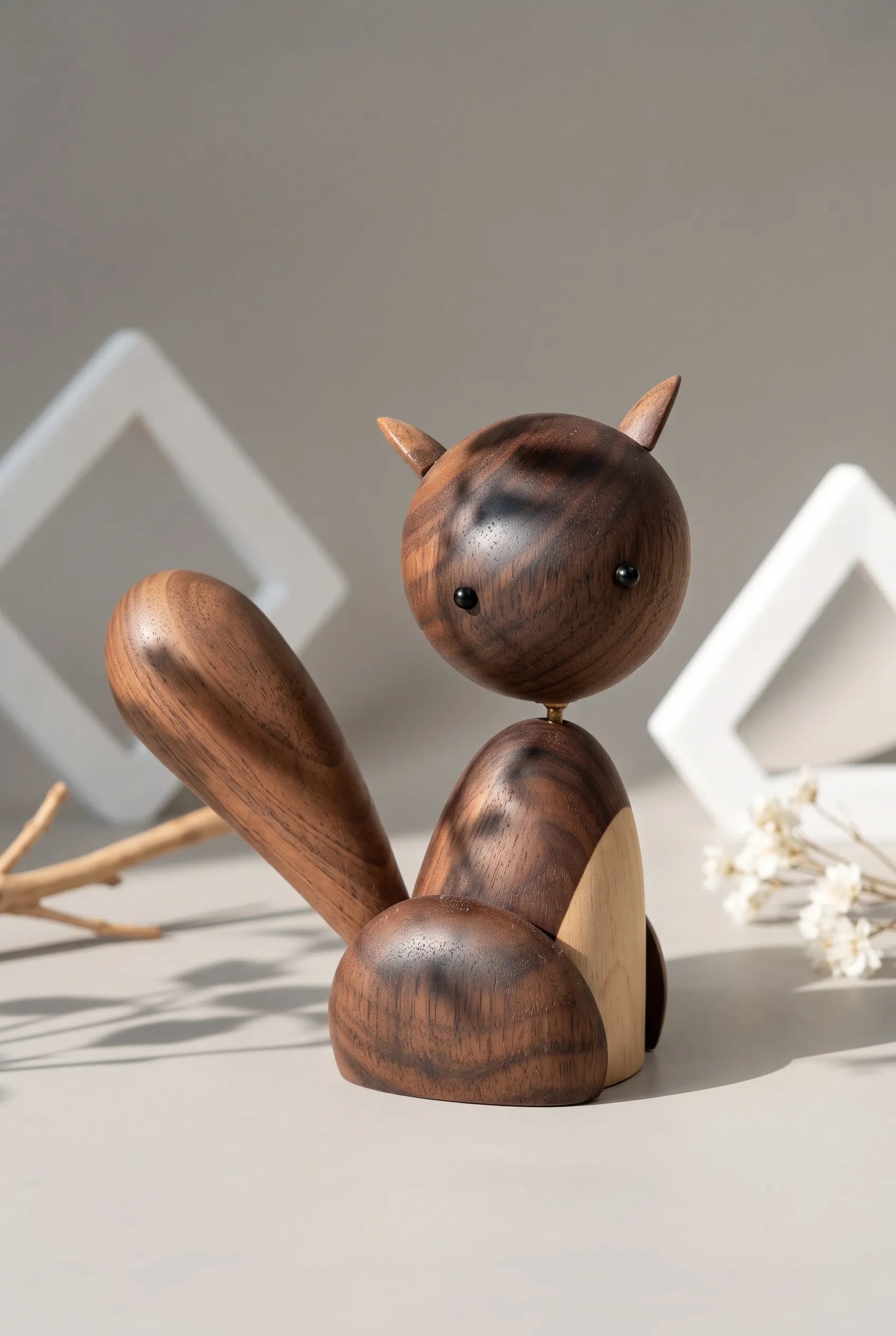 Nordic black walnut squirrel sculpture under soft botanical shadows that reveal its polished grain.
