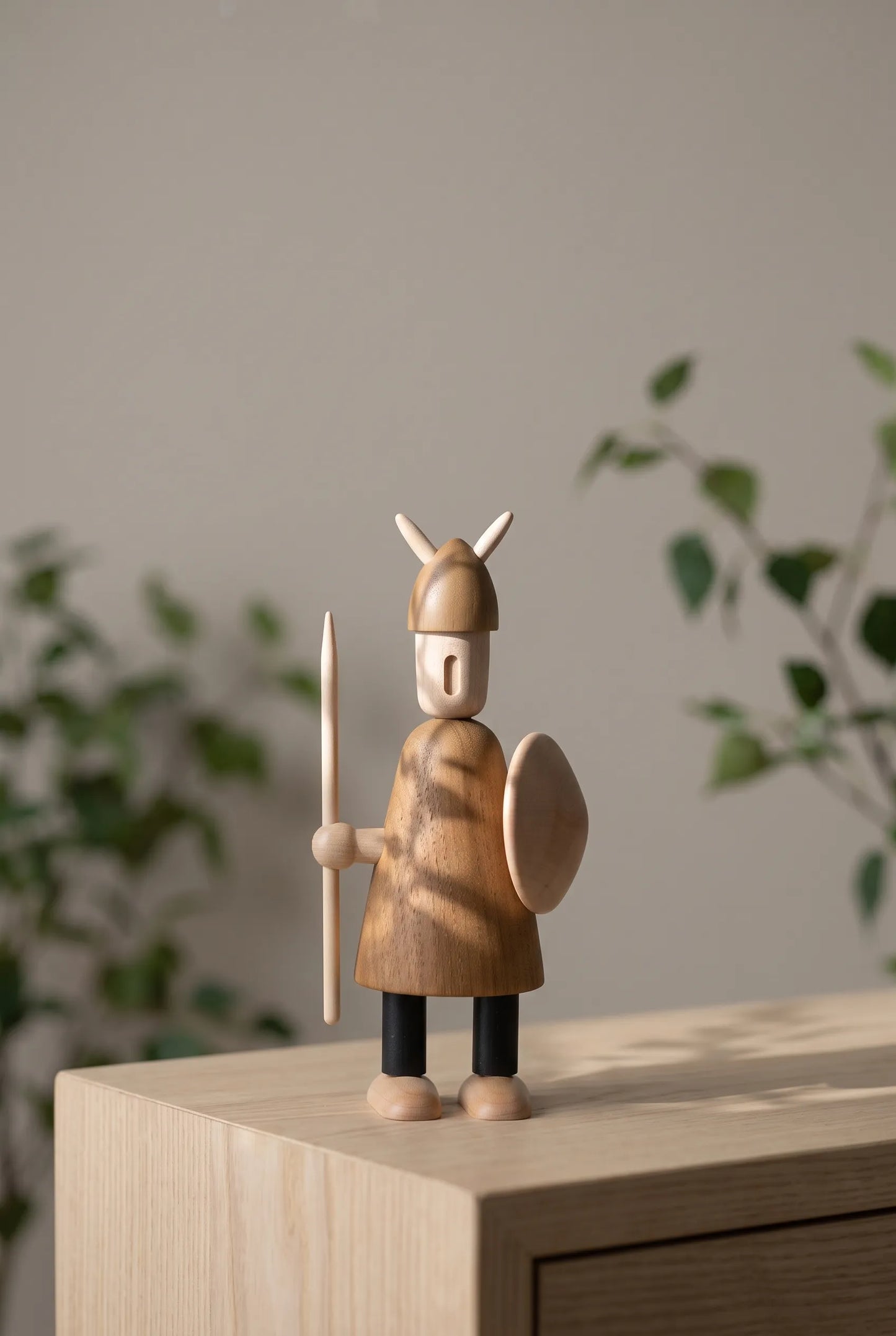 Nordic Mythos Viking Wood Sculpture crafted from Solid Teak and Natural Maple Wood with light-absorbing matte wood grain finish, resting under soft botanical shadows and natural sunlight.