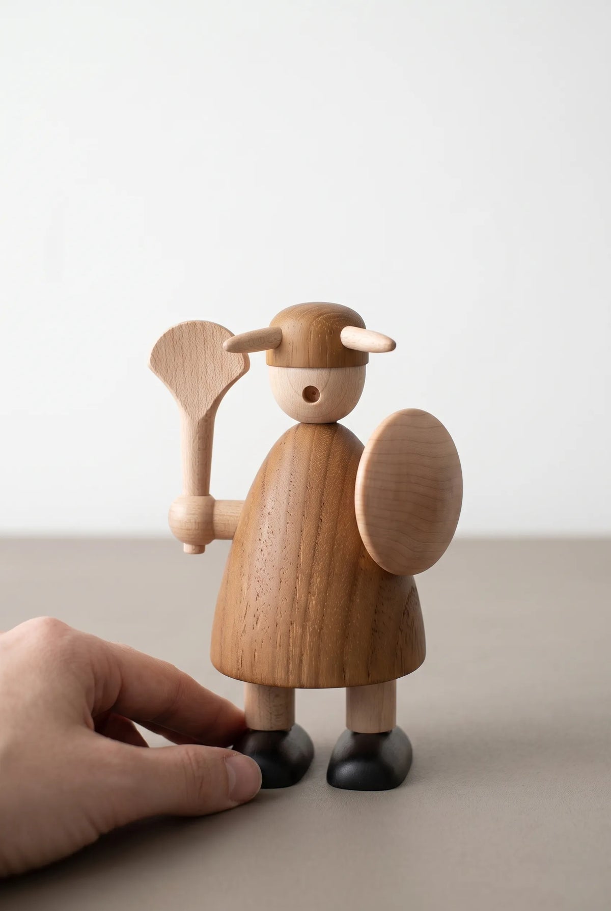 Nordic Mythos Viking Wood Sculpture crafted from Solid Teak and Natural Maple Wood with glare-free matte finish, touched gently by a relaxed hand at the lower frame edge.