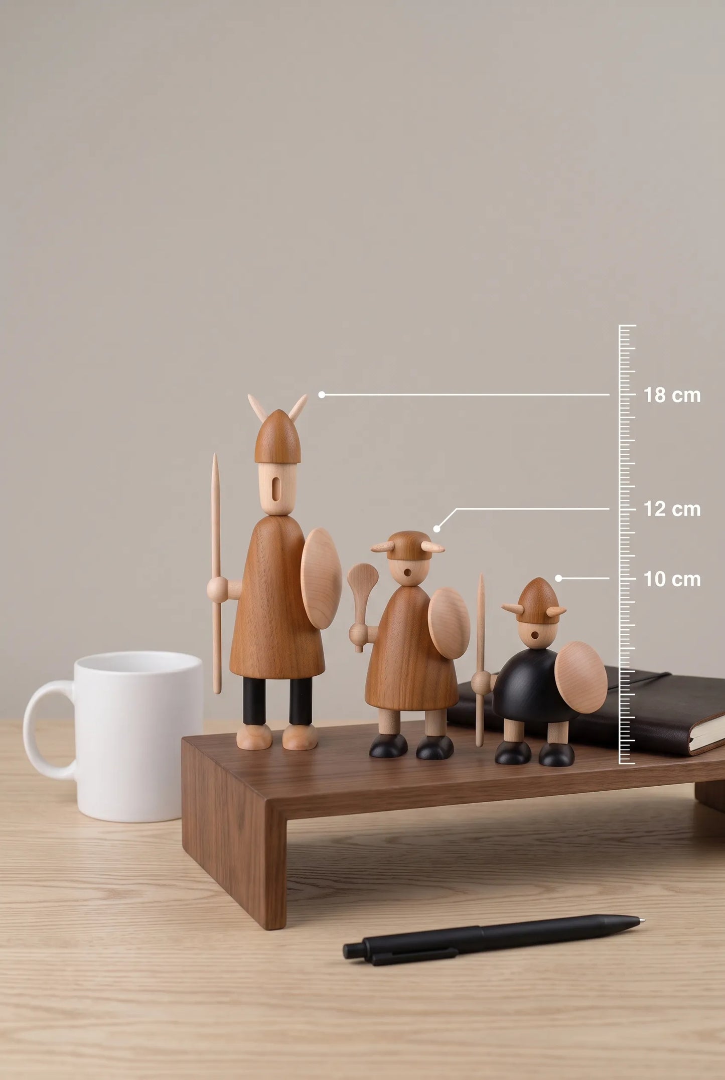Nordic Mythos Viking Wood Sculptures measuring 18cm, 12cm, and 10cm, crafted from Solid Teak and Natural Maple, juxtaposed with unbranded everyday desk objects for scale.