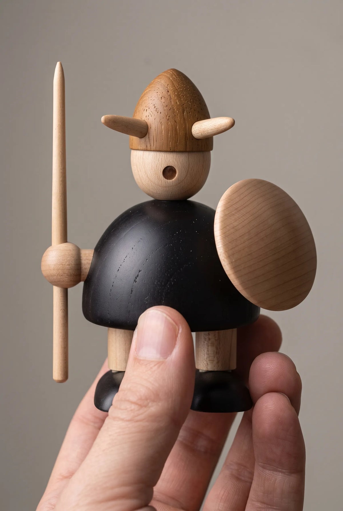 Nordic Mythos Viking Wood Sculpture crafted from solid teak and natural maple wood with glare-free matte natural wood finish, touched gently by a relaxed hand at the lower frame edge.